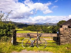 Bicycle leaning against 5-bar gate, overlooking farmland